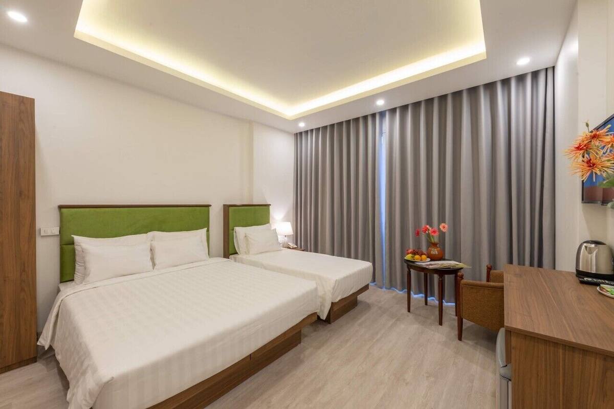 A hotel room with two beds, a desk, and a chair.