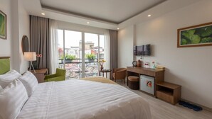 A hotel room with a large bed, a desk, a chair, a television, and a balcony with a view of buildings. - AMI Old Quarter Hotel (Hanoi)