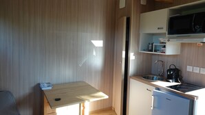 Una cocina compacta equipada con microondas, estufa, pileta y un refrigerador pequeño.