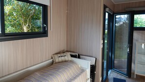 Un dormitorio con cama, ventana y puerta corrediza de vidrio que da a un espacio exterior.