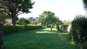 Un jardín bien cuidado, con diversos árboles y un seto recortado.