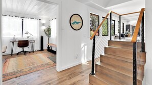 Un intérieur moderne avec un escalier en bois, un bureau avec une chaise et un grand tapis.