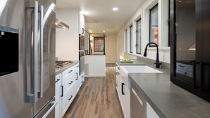 Een moderne keuken met roestvrijstalen apparatuur, een centraal eiland en een groot raam voor natuurlijk licht.