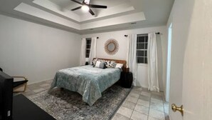 A bedroom with a bed, a ceiling fan, a rug, and a door.