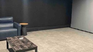 A dark room with a single blue leather sofa, a small round table, and a coffee table.