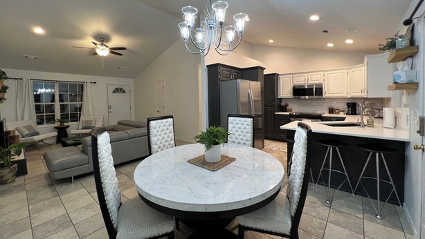 A modern kitchen with a central island, dark cabinetry, and a dining area with a round table and four chairs.