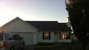 A single-story house with a garage, a driveway, and a lawn.