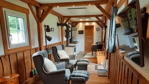 Interior acolhedor de cabana com lareira, paredes de madeira e área de estar com sofá e pufes.
