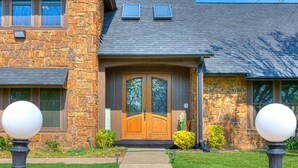A stone house with a wooden front door, two windows, and a pathway leading to the entrance. - POOL, HOT TUB, AMAZING TURF, GAMES GALORE LUXURY VILLA IN OKC (Oklahoma City)