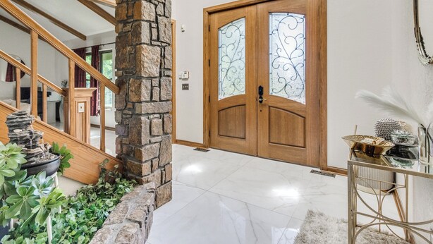 A foyer with a stone pillar, a wooden door with glass panels, a chandelier, and a staircase. - POOL, HOT TUB, AMAZING TURF, GAMES GALORE LUXURY VILLA IN OKC (Oklahoma City)