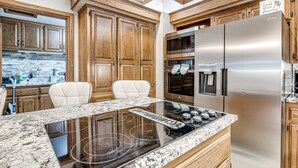 A modern kitchen with wooden cabinets, a stainless steel refrigerator, an LG oven, and a granite countertop. - POOL, HOT TUB, AMAZING TURF, GAMES GALORE LUXURY VILLA IN OKC (Oklahoma City)
