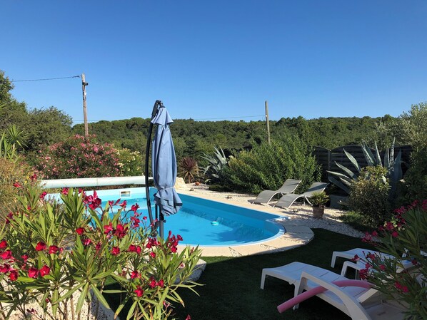 Una piscina rodeada de sillas de descanso y una sombrilla.