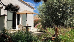 Un bâtiment blanc doté d’un patio, d’une table avec des chaises et d’un parasol.