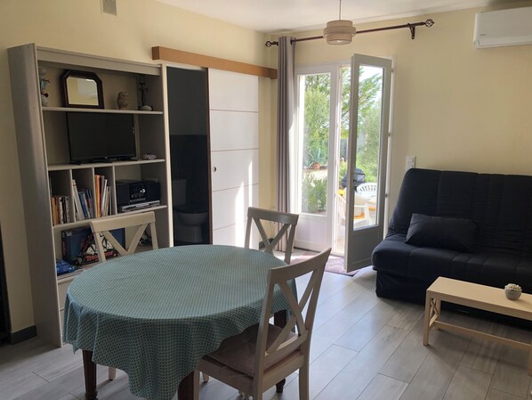 A living room with a dining table, a sofa, and a bookshelf.
