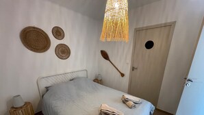 A bedroom with a bed, a wooden door, a wall-mounted towel rack, and a hanging light fixture.