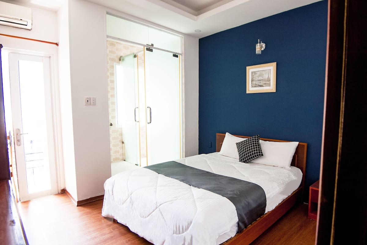A bedroom with a bed, a wardrobe, and a door leading to a bathroom.