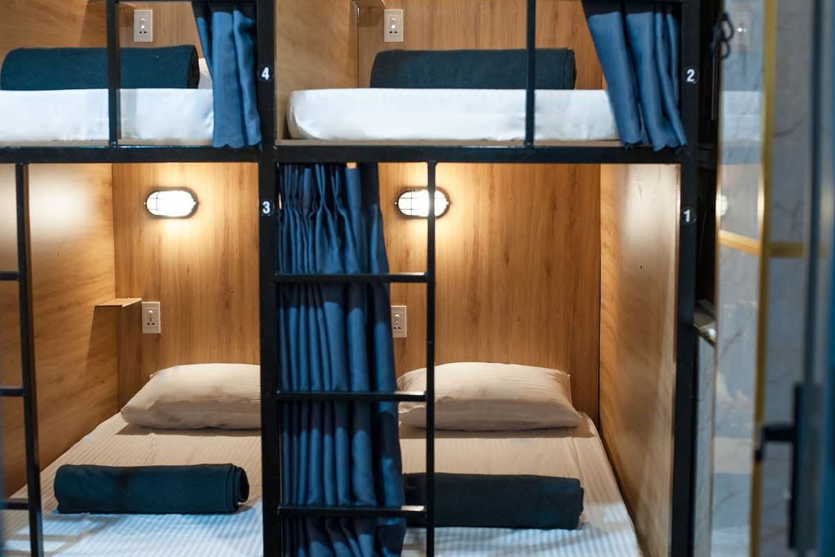 A bunk bed room with wooden walls, two beds, and a small window.