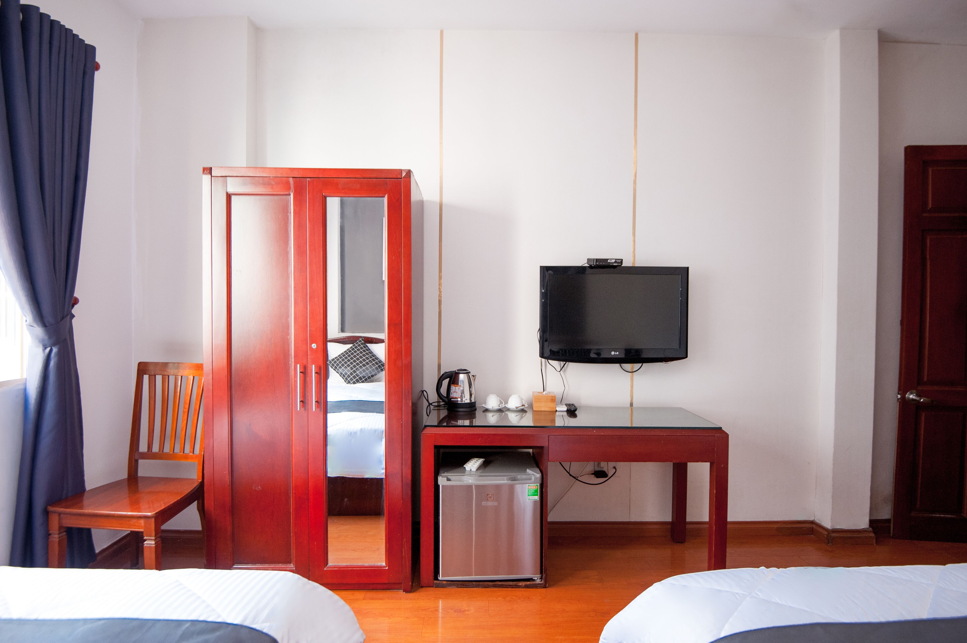 Ein Hotelzimmer mit einem Bett, einem Holzstuhl, einem Schreibtisch mit Fernseher und einer Minibar.