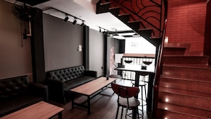 A modern interior with a black leather sofa, wooden tables, and red brick walls.