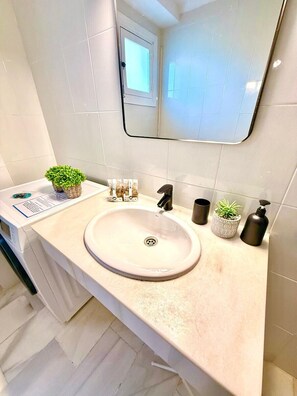 Ein Badezimmer mit Waschbecken, Spiegel und Pflegeprodukten.