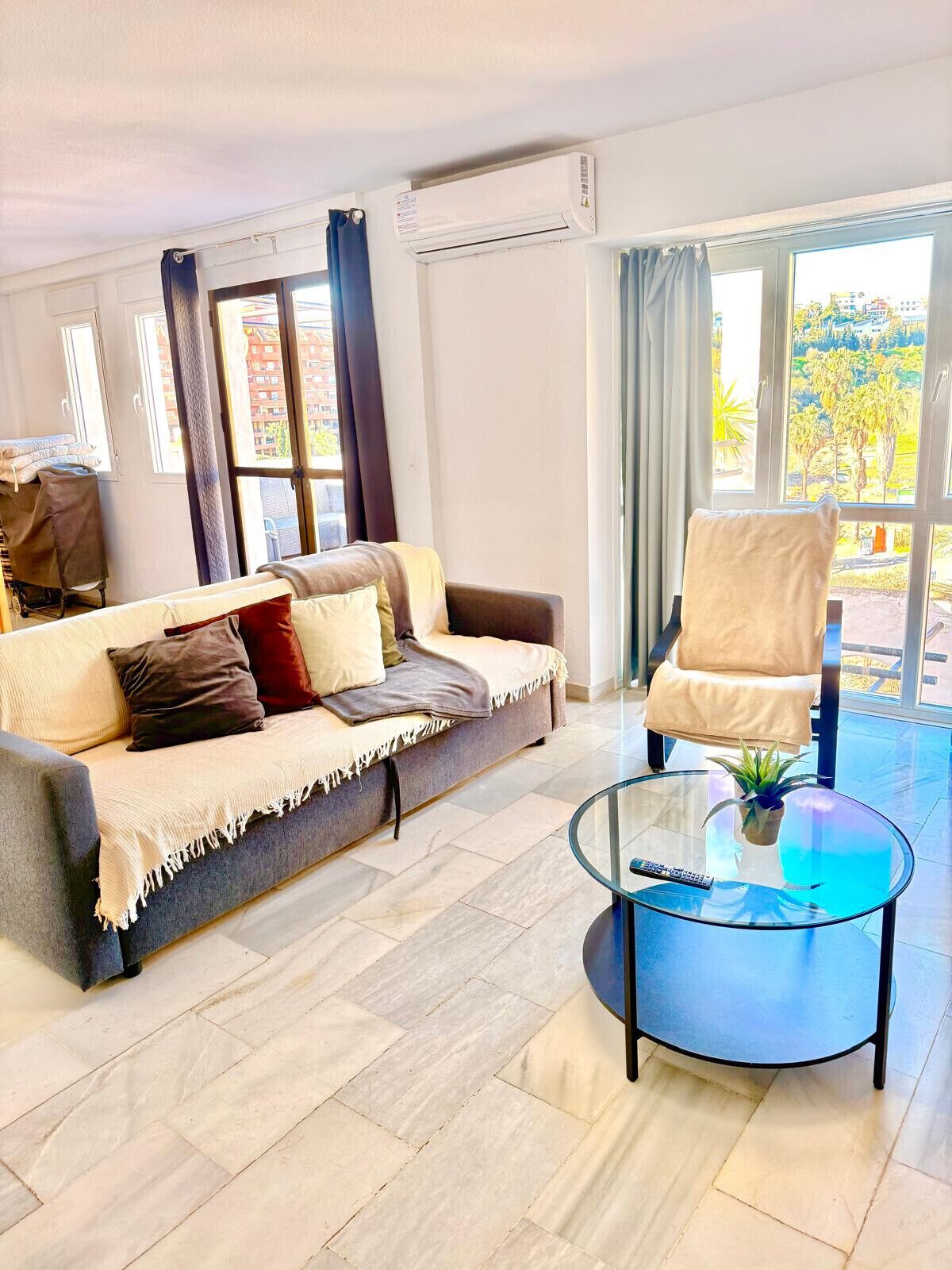 Una sala de estar moderna con un sofá, un sillón y una mesa de centro de vidrio.