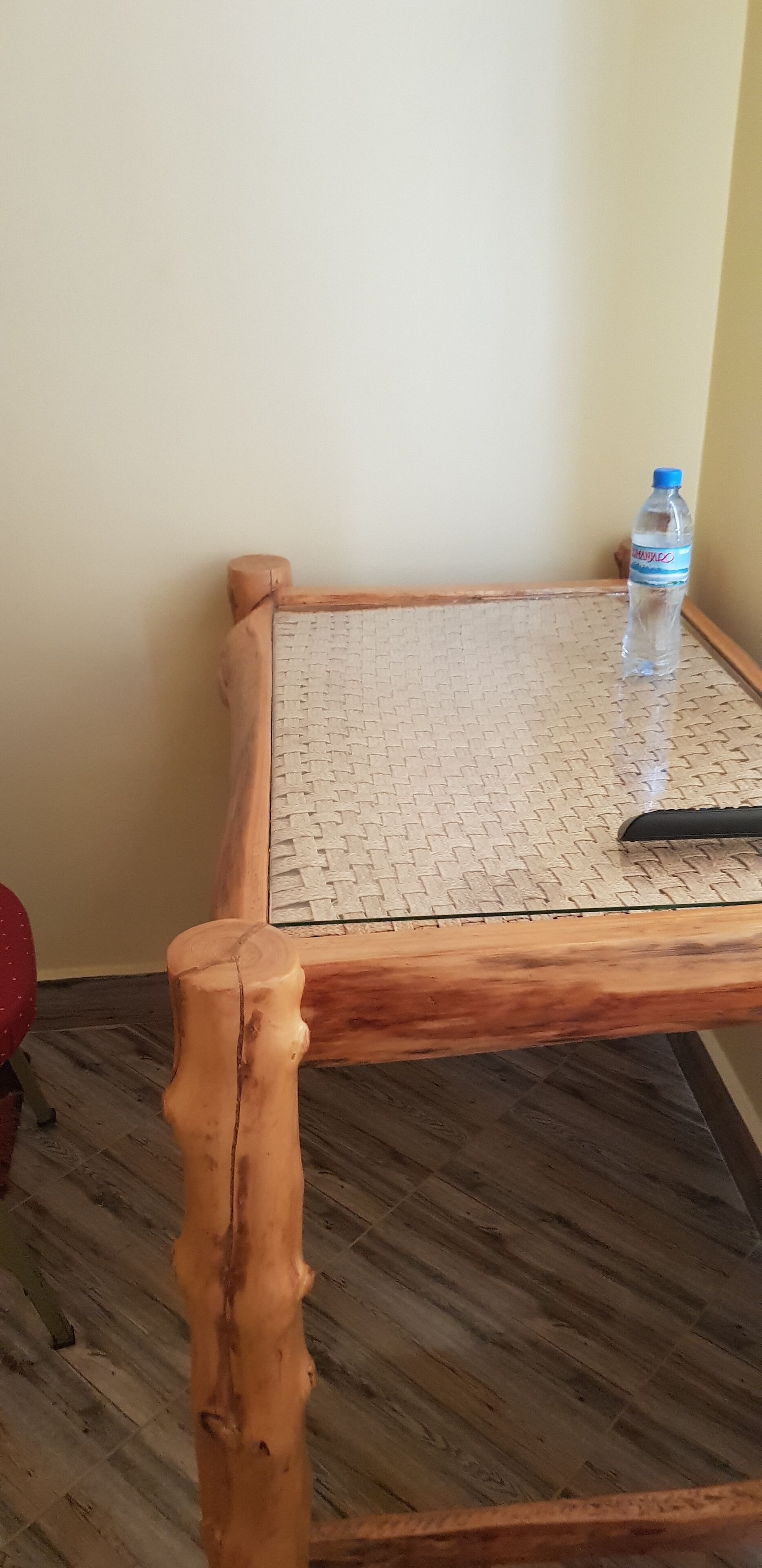 A wooden table with a woven tabletop, a water bottle, and a black object on it.