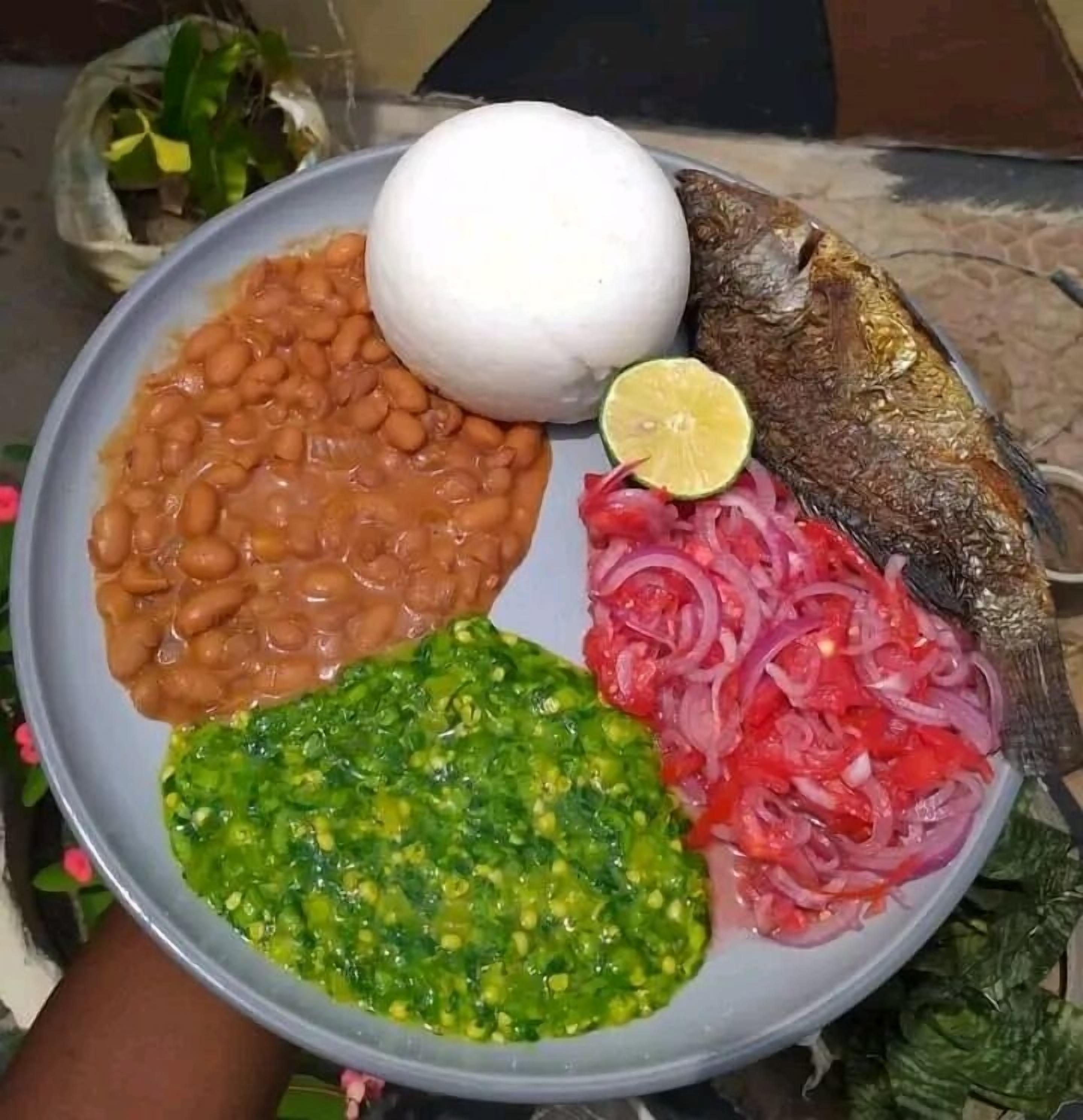 A plate with beans, fish, and a lime slice.