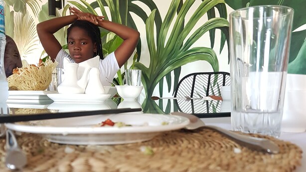 A dining table with a woven placemat, plates, cutlery, and a glass of water. - Tanzanin Eco Home & Camp (Arusha)
