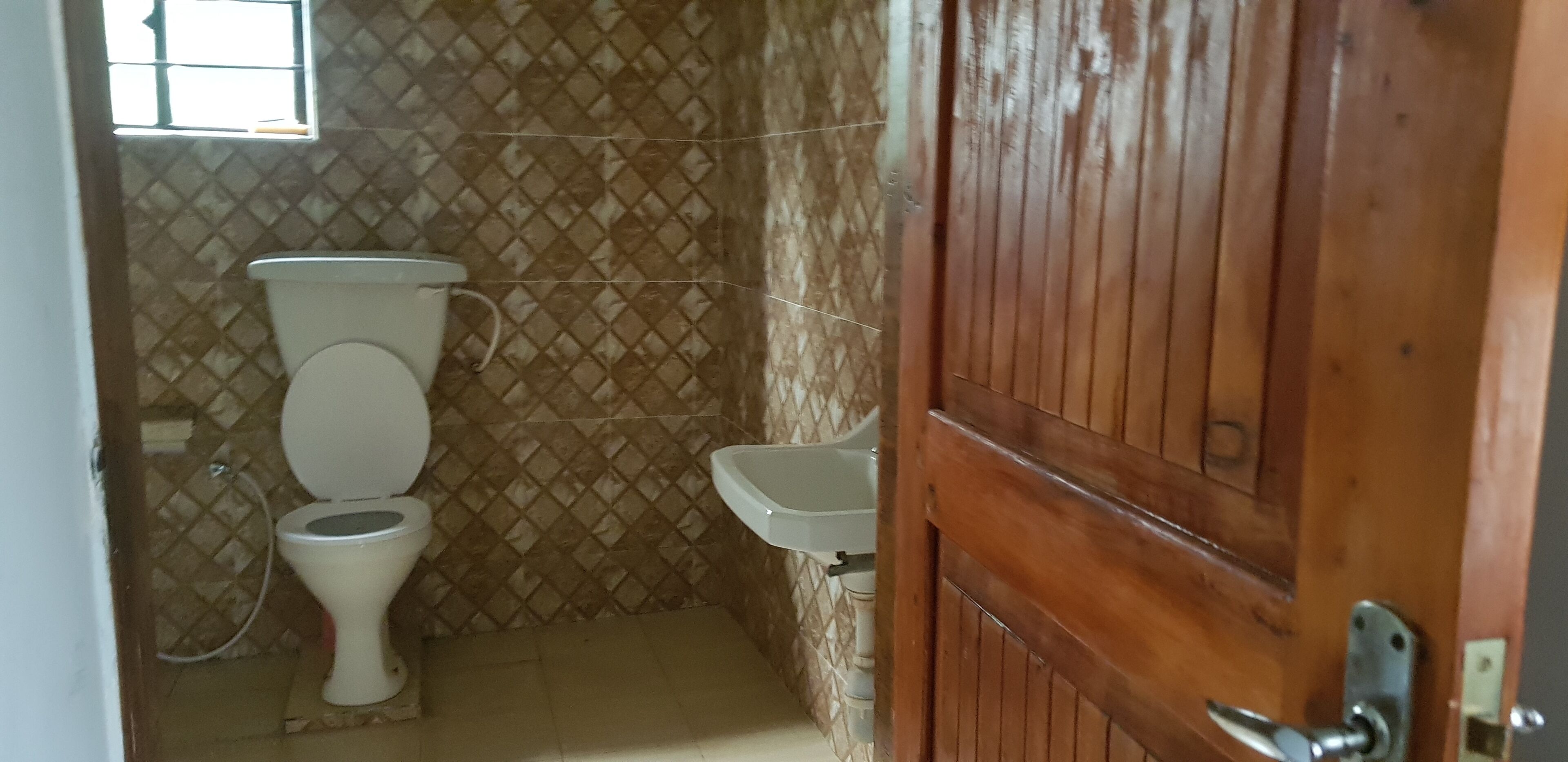 A bathroom with a toilet, sink, and tiled walls.