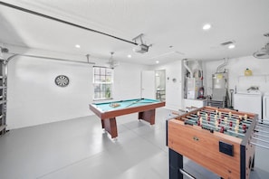 Une pièce spacieuse équipée d’une table de billard, d’un baby-foot et d’un jeu de fléchettes.