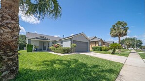 A residential area with houses, well-maintained lawns, and palm trees.