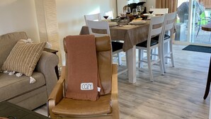 Una sala de estar acogedora con comedor, un sofá, una mesa de centro y una silla con la etiqueta 'COZY'.