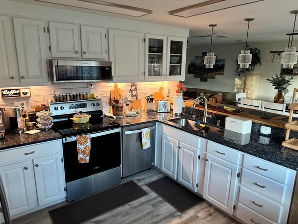 A modern kitchen with white cabinets, stainless steel appliances, and a granite countertop. - Sanctuary of Comfort and Peace Olympic Mountains view. (Port Angeles)