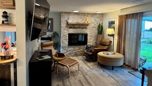 Un salon moderne avec une cheminée en pierre, des meubles en cuir et un téléviseur à écran plat.