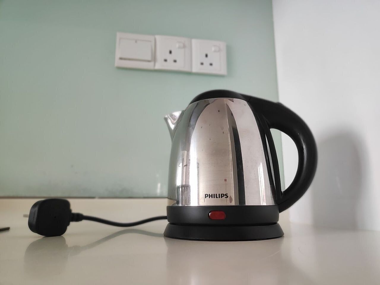 A Philips electric kettle with a black base and handle, connected to a power cord, placed on a white surface.