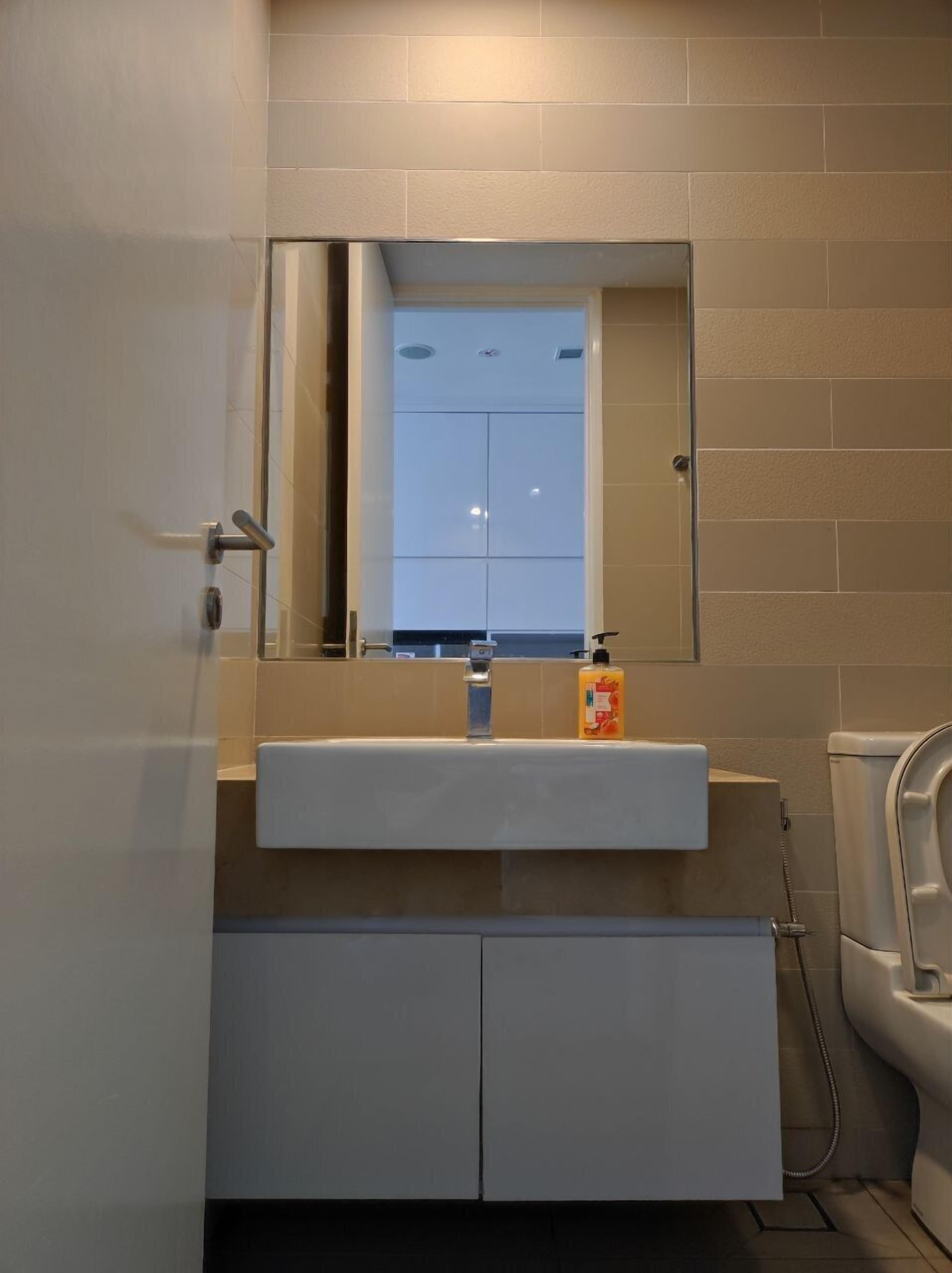 A bathroom with a white sink, a mirror, and a toilet.