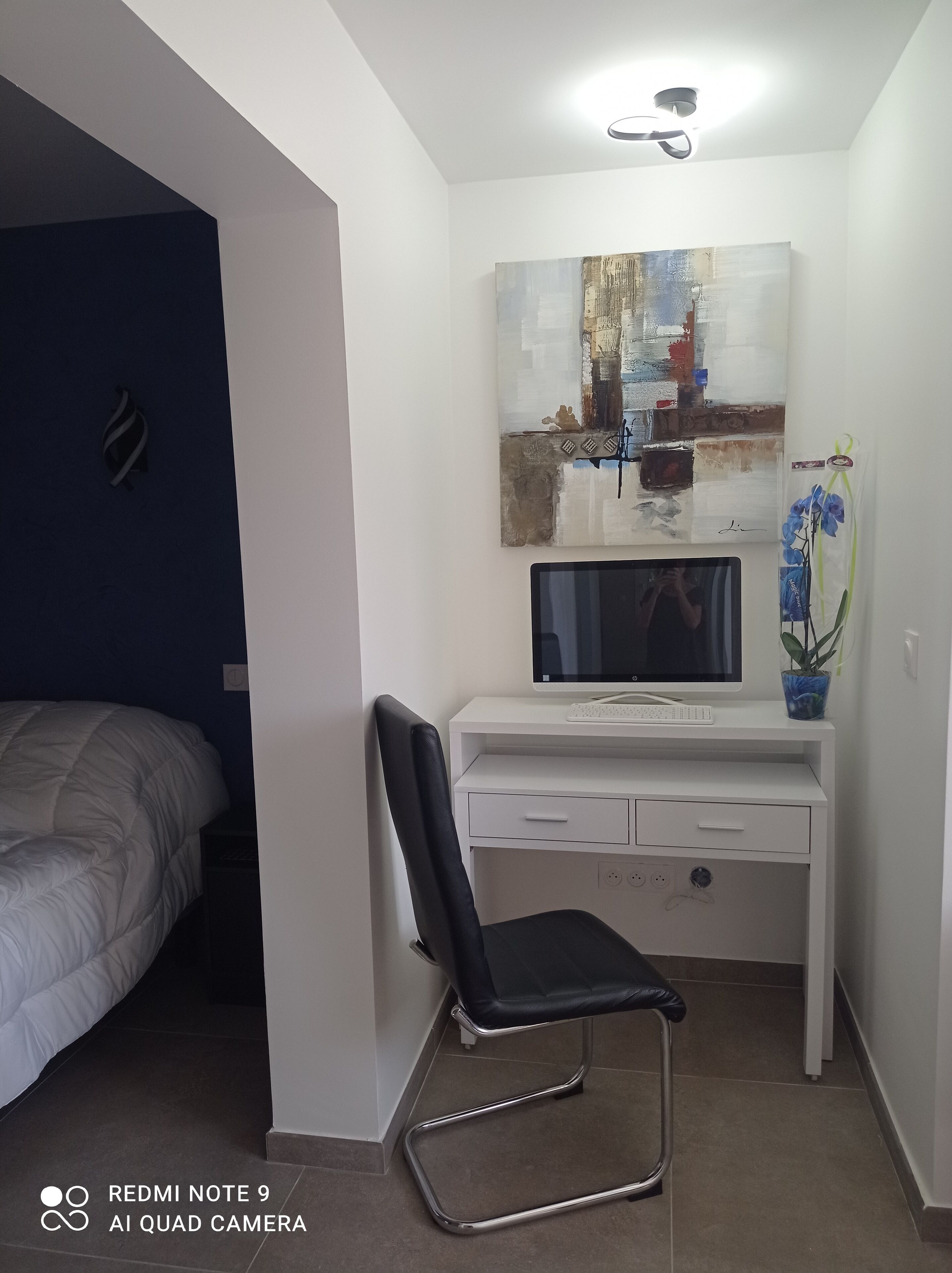 A bedroom with a bed, a desk with a computer, and a chair.