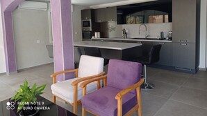 A modern kitchen with a central island, built-in appliances, and a dining area with two chairs. - Location Estivale Bastia U Fiumicellu, Vue Mer. Jacuzzi, Barbecue, (Bastia)