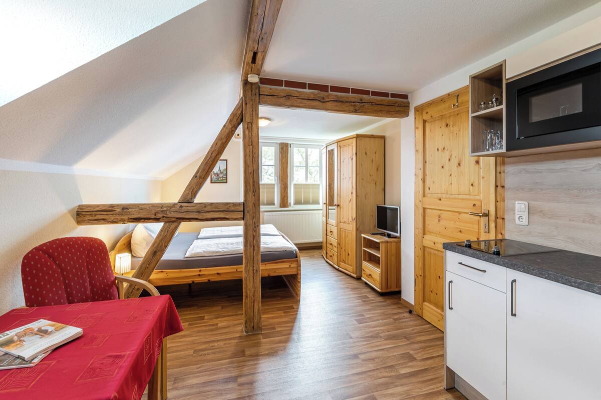 Une pièce compacte avec un lit en mezzanine, des meubles en bois, une petite télévision et une table à manger.