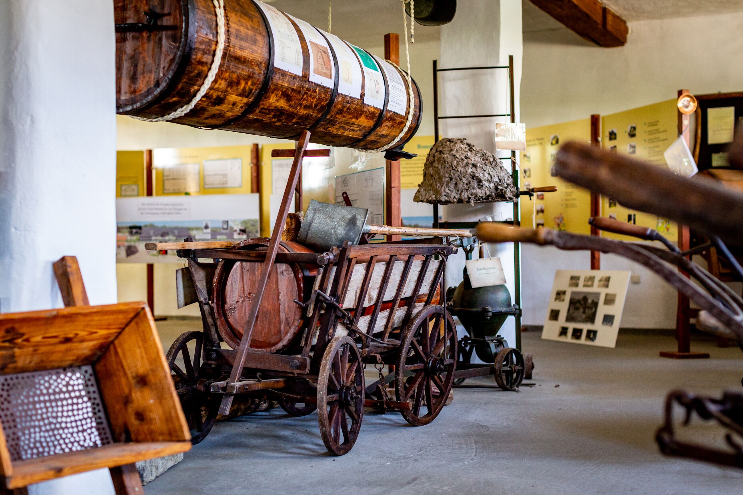 Un interior rústico con barriles de madera, un carro de madera y una lámpara colgante.