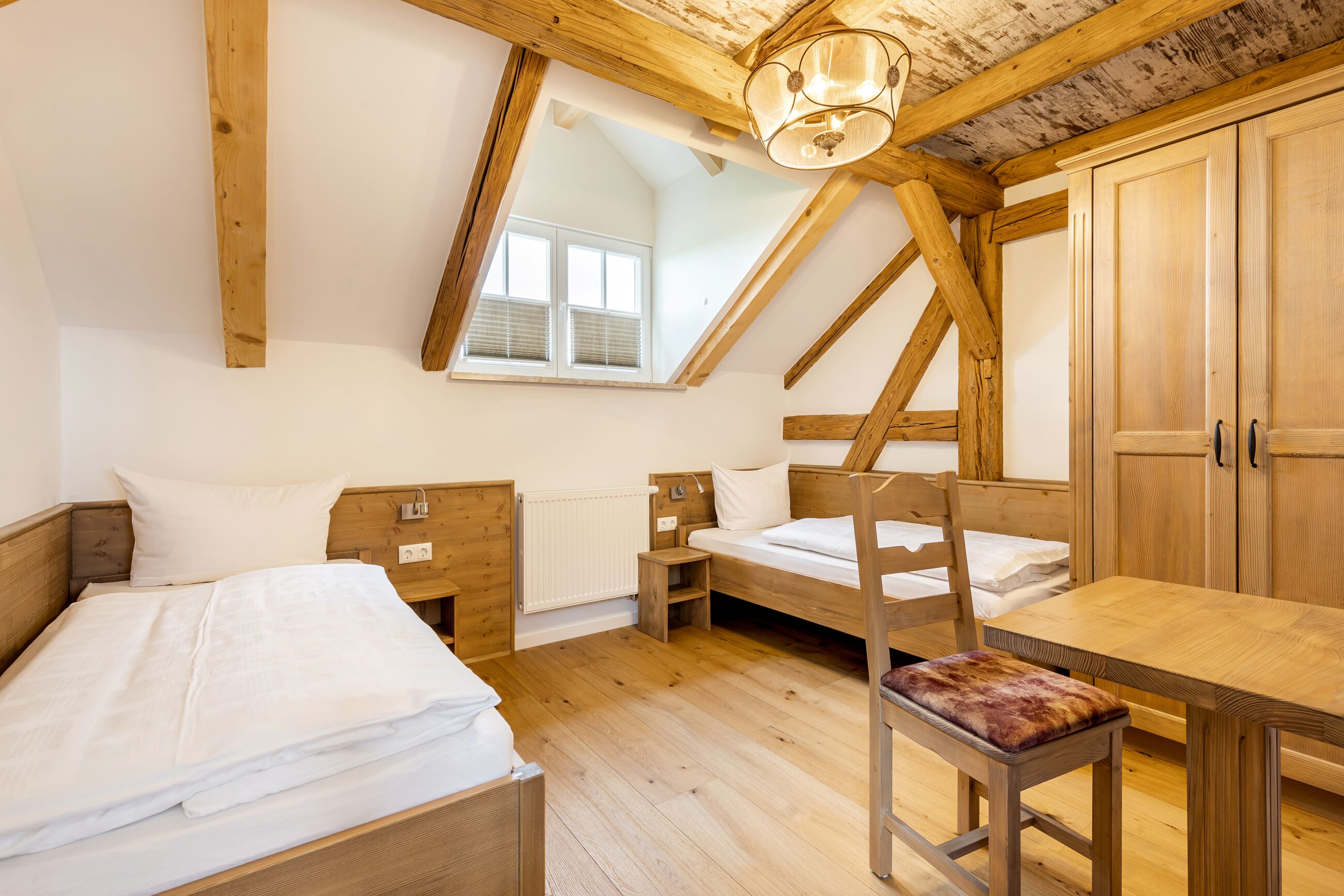 Un dormitorio con dos camas, una mesa de madera y una silla.