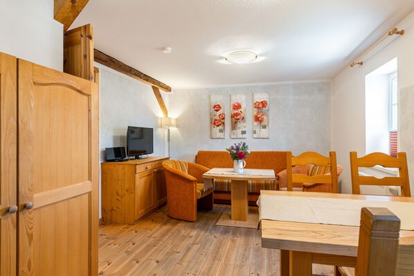 A cozy room with wooden furniture, a television, and artwork on the wall. - Ferienhof Domäne Groschwitz (Rudolstadt)