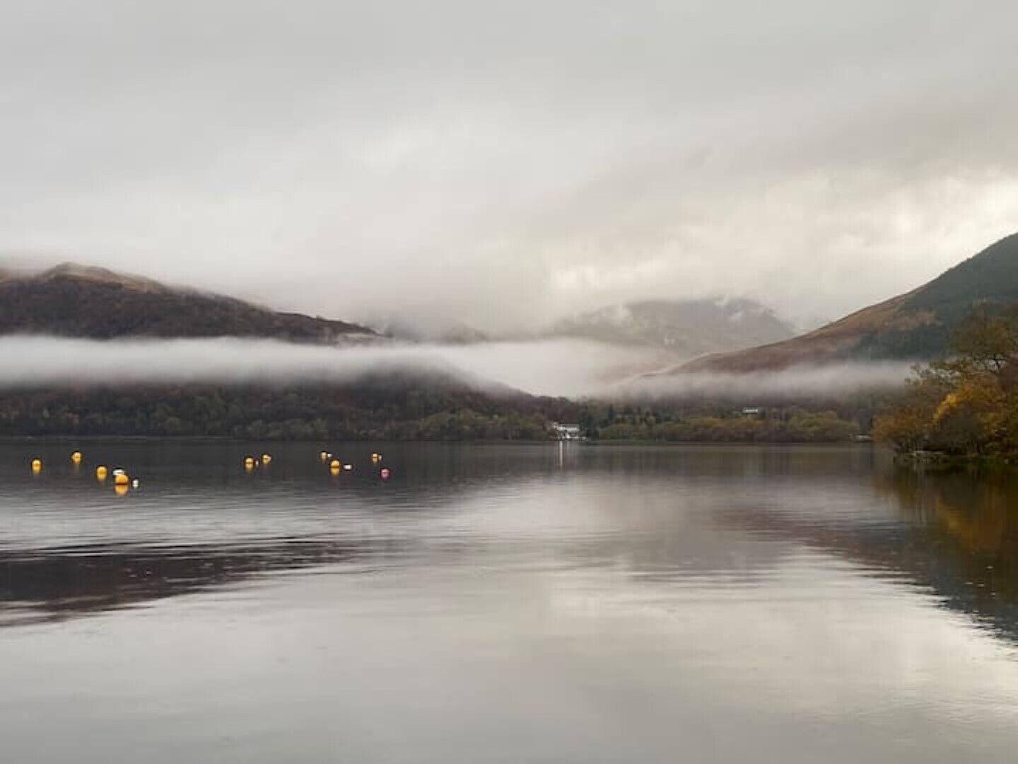 A calm lake with mountains in the background and a misty atmosphere.