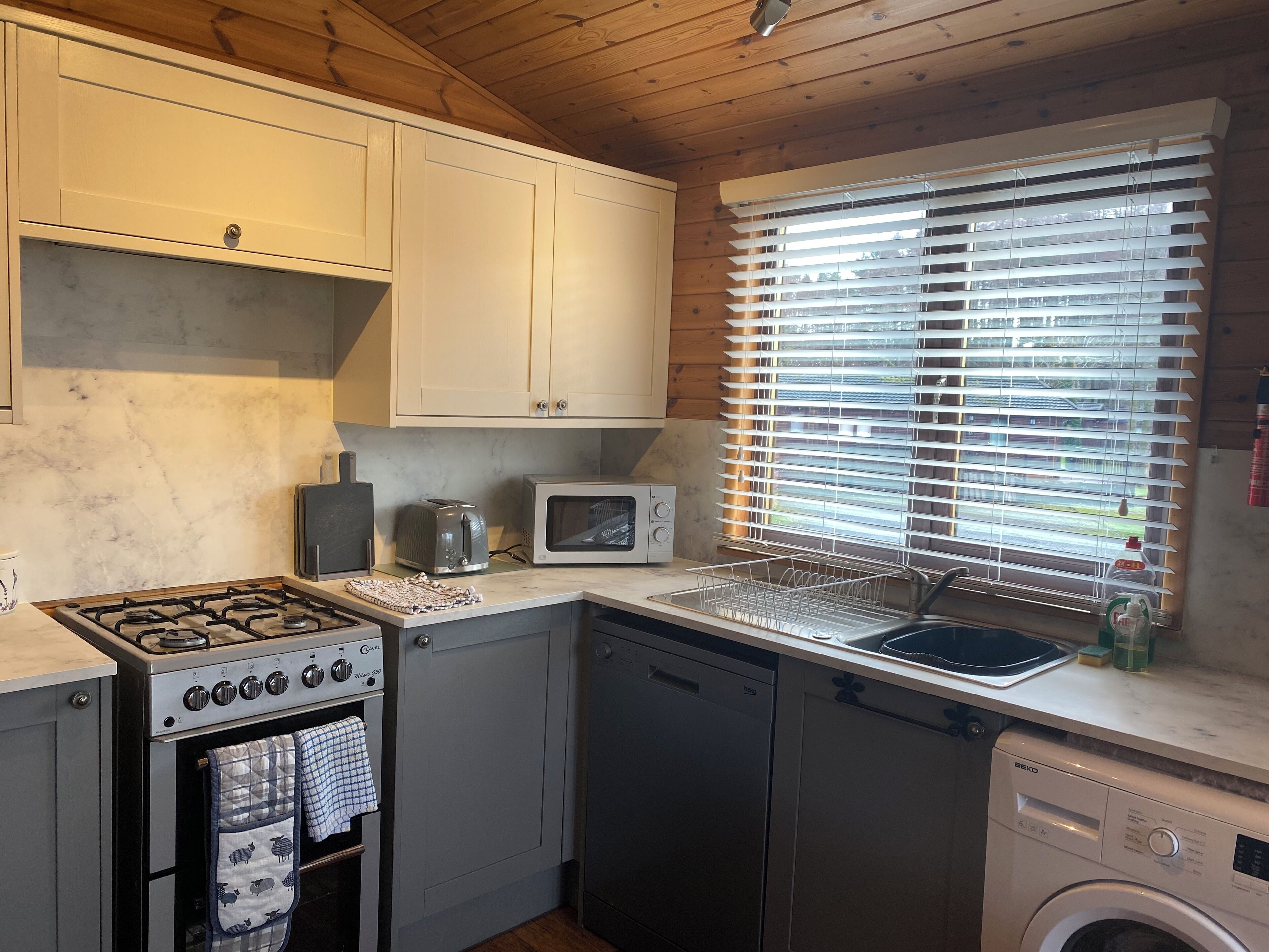 A compact kitchen with a gas stove, microwave, dishwasher, and a washing machine.