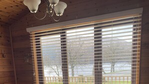 A wooden dining room with a table set for four, a bowl in the center, and a window with blinds.