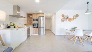 A modern kitchen with white cabinets, a stainless steel refrigerator, and wooden accents. - 0069-MIMOSES Modern apartment near the beach (Empuriabrava)