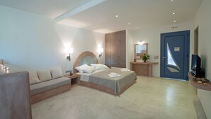 A modern hotel room with a bed, a sofa, a TV, and a bathroom. - ANEMES (Kithira)