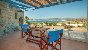 A terrace with a stone wall, wooden furniture, and a table set for a meal. - ANEMES (Kithira)