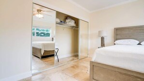 A bedroom with a bed, a nightstand, a lamp, a wardrobe, and a ceiling fan.