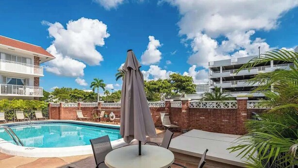 A poolside area with a pool, lounge chairs, and a table with an umbrella.